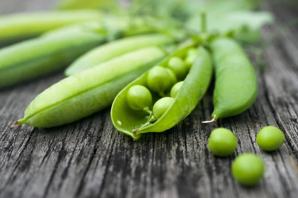 Vainas de guisantes verdes en una superficie de madera vieja —  Fotos de Stock