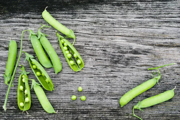 Des gousses de pois verts sur une vieille surface en bois — Photo