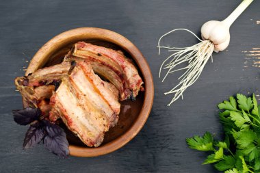 Kızarmış domuz kaburga bir ahşap kase ve bir tablo taze yeşillik.