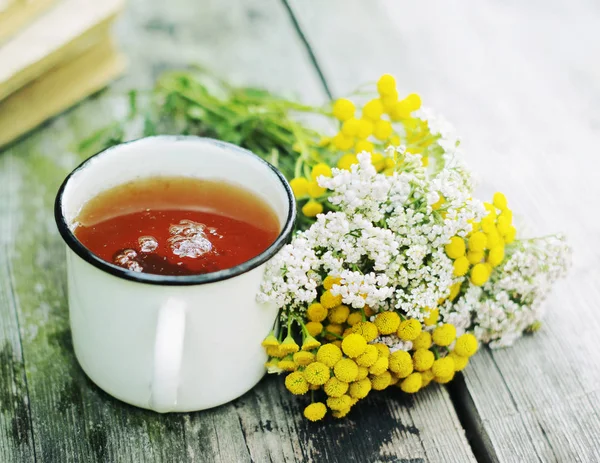 Chá de ervas em um copo e branca yarrow flores na superfície de madeira velha. Chá e ervas. Medicina alternativa — Fotografia de Stock