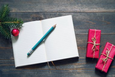 Boş defter, kalem ve hediye ya da tahta zemin üzerinde kırmızı kutular, metin için boşluk ile üst görünüm düz bir stil.