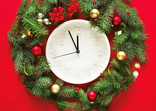 赤の背景に休日の装飾で白い丸時計とモミの枝 トップビュー クリスマスの冬の背景 クリスマスカード — ストック写真