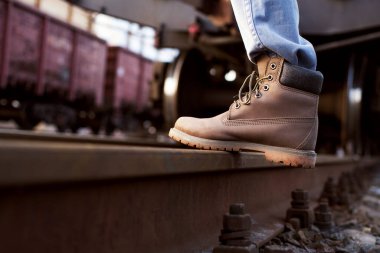 Girl in boots walks through the railroad tracks in autumn
