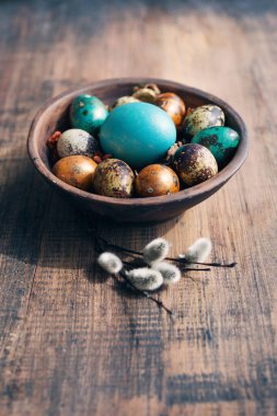 Kil kasede parlak paskalya yumurtaları ve eski ahşap arka planda yumuşak söğüt dalları..