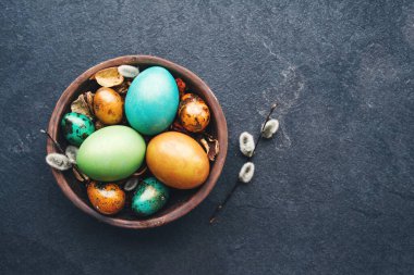 Kil kasede parlak paskalya yumurtaları ve arka planda kabarık söğüt dalları, üst manzara. Paskalya arkaplanı.