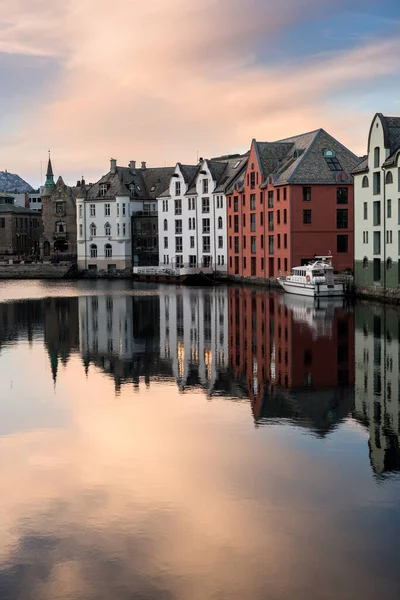 Norveç, Aalesund 'da sudan yansıyan güzel binaların dikey gün batımı fotoğrafı..