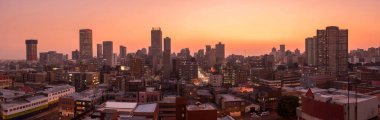 Johannesburg şehir siluetinin güzel ve dramatik bir fotoğrafı, gün batımından sonra altın bir akşamda çekildi..