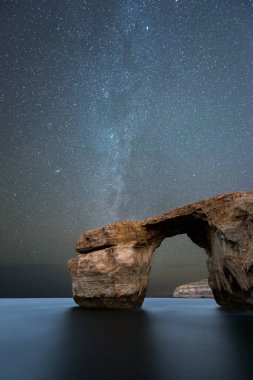 Güzel bir dikey Samanyolu gece gökyüzü fotoğrafı Malta 'nın Gozo adasındaki Azure Pencere kaya kemerinin..