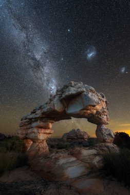 Arka planda Samanyolu ve Macellan Bulutları olan inanılmaz bir kaya kemerinin dramatik bir dikey gece manzarası fotoğrafı, Güney Afrika 'daki Cederberg dağlarında çekildi..