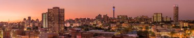 Johannesburg şehir siluetinin güzel ve dramatik bir fotoğrafı, gün batımından sonra altın bir akşamda çekildi..