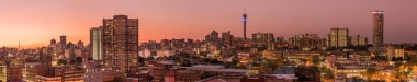 A beautiful and dramatic panoramic photograph of the Johannesburg city skyline, taken on a golden evening after sunset. clipart