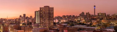 Johannesburg şehir siluetinin güzel ve dramatik bir fotoğrafı, gün batımından sonra altın bir akşamda çekildi..
