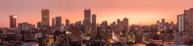 Johannesburg şehir siluetinin güzel ve dramatik bir fotoğrafı, gün batımından sonra altın bir akşamda çekildi..