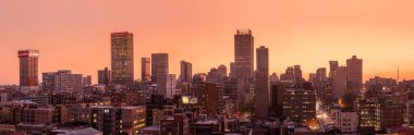 Johannesburg şehir siluetinin güzel ve dramatik bir fotoğrafı, gün batımından sonra altın bir akşamda çekildi..