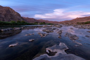 Gün batımından sonra, Richtersveld Güney Afrika 'sında çekilen su yüzeyine çarpıcı turuncu bulutların yansıdığı, dağlarla ve Orange Nehri' yle çekilen güzel, uzun bir manzara..