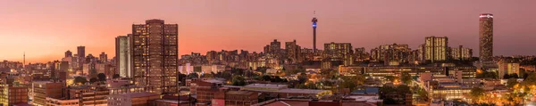Johannesburg şehir siluetinin güzel ve dramatik bir fotoğrafı, gün batımından sonra altın bir akşamda çekildi..
