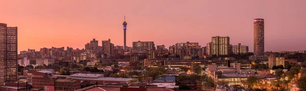 Johannesburg şehir siluetinin güzel ve dramatik bir fotoğrafı, gün batımından sonra altın bir akşamda çekildi..
