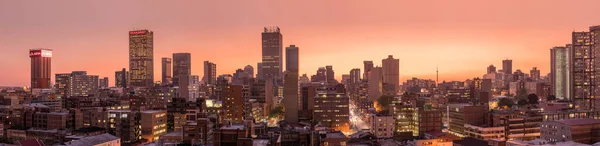 Johannesburg şehir siluetinin güzel ve dramatik bir fotoğrafı, gün batımından sonra altın bir akşamda çekildi..