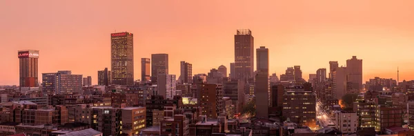 Johannesburg şehir siluetinin güzel ve dramatik bir fotoğrafı, gün batımından sonra altın bir akşamda çekildi..