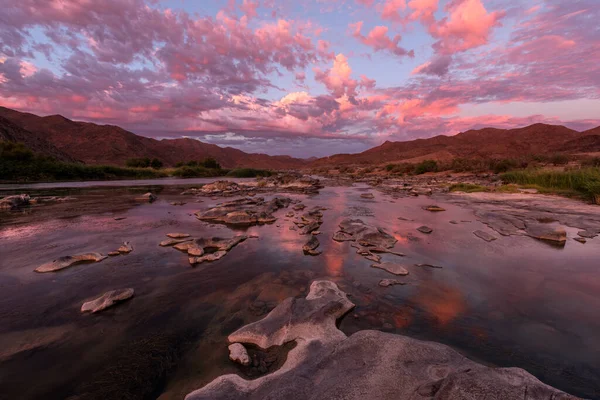 Gün batımından sonra, Richtersveld Güney Afrika 'sında çekilen su yüzeyine çarpıcı turuncu bulutların yansıdığı, dağlarla ve Orange Nehri' yle çekilen güzel, uzun bir manzara..