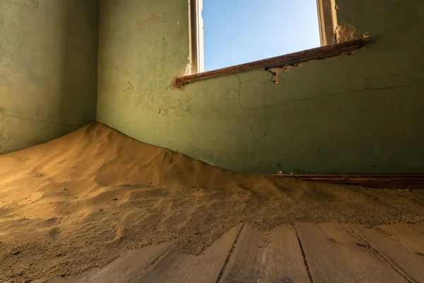 Terk edilmiş bir evin köşesinde çöl kumları olan eski, kırık bir pencerenin yakın plan fotoğrafı, Namibya 'nın hayalet kasabası Kolmanskop' ta çekildi..