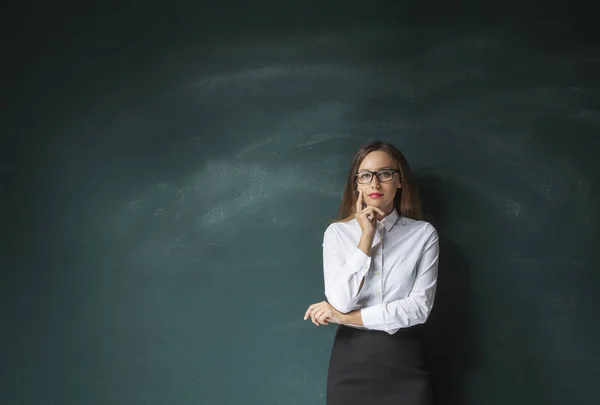 Doordachte jonge vrouw op schoolbord achtergrond — Stockfoto