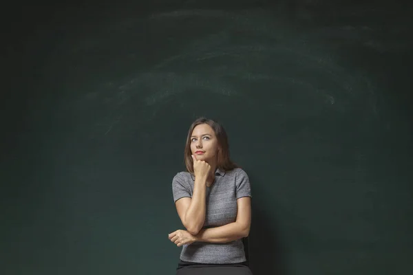 Pensativo jovem mulher no quadro de chalkboard fundo — Fotografia de Stock