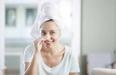 Genç bir kadın yüzünü pamukla temizliyor.