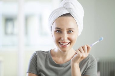 Elinde diş fırçası tutan gülümseyen sevimli bir kadının portresi.