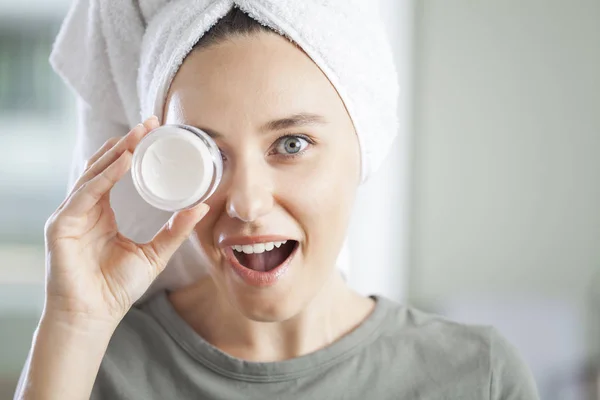 Mujer joven aplicando crema hidratante en su piel —  Fotos de Stock