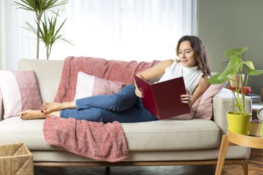Evde kitap okuyan genç bir kadın.