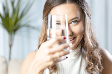 Camdan kameraya bakarken gülümseyen genç bir kadın.