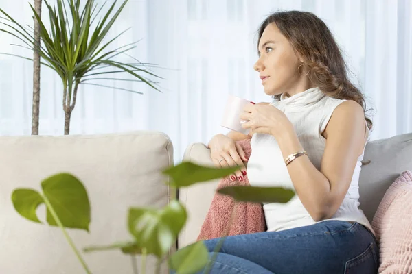 Een vrouw die thuis denkt. Bedachtzame vrouw kijkt weg terwijl drin — Stockfoto