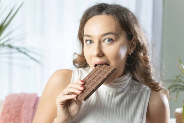 Молодая женщина наслаждается шоколадным батончиком в доме — стоковое фото