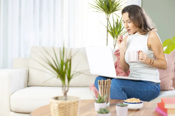 Jonge vrouw met laptop op sof — Stockfoto