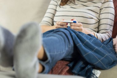 Hasta kadın evde ateşini ölçüyor.