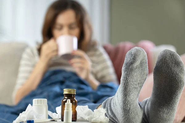 Chora kobieta odpoczywa na kanapie trzymając gorącą filiżankę herbaty. — Zdjęcie stockowe