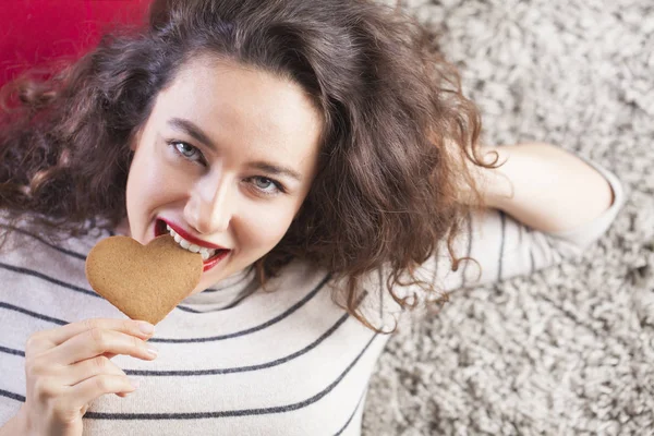 Молодая женщина ест печенье в форме сердца — стоковое фото