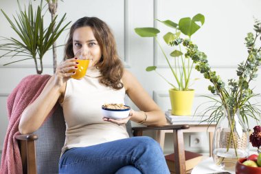 Mısır gevreği ve portakal suyuyla kahvaltı eden bir kadın.