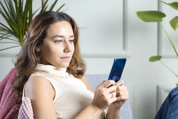 Young woman using mobile phone at hom — Stock Photo, Image