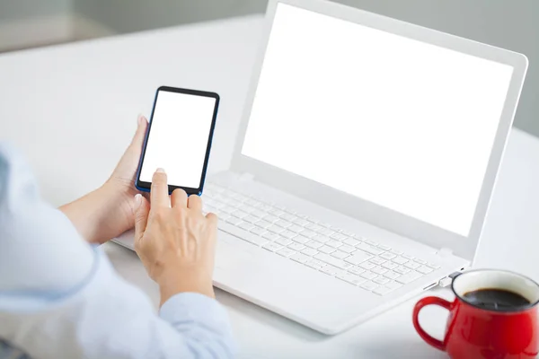 Kobieta Trzymająca Biały Ekran Smartfona Pusty Biały Ekran Laptopa Biurku — Zdjęcie stockowe