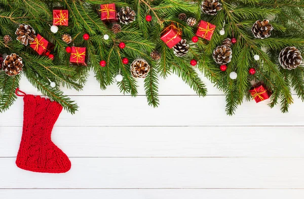 Weihnachtlicher Hintergrund. Weihnachten Tanne mit Dekoration mit Socke auf weißem Holzbrett Hintergrund. — Stockfoto
