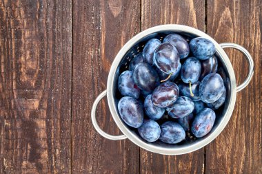 Eski ahşap masa üzerinde rustik kevgir içinde mavi Erik. Organik gıda. Kopya alanı