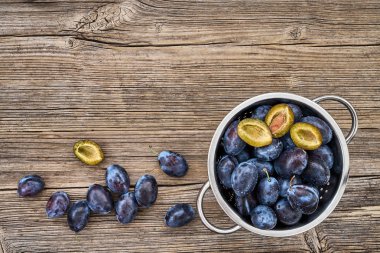 Eski ahşap masa üzerinde kevgir içinde taze mavi Erik. Organik gıda. Üstten Görünüm