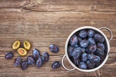 Eski ahşap masa üzerinde rustik kevgir içinde taze mavi Erik. Organik gıda. Üstten Görünüm, kopya alanı