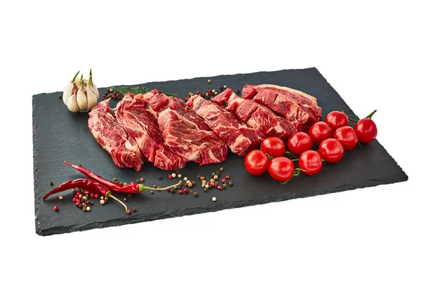 Biber ve domates siyah arduvaz tahta üzerinde taze çiğ dana biftek. Beyaz bitti izole