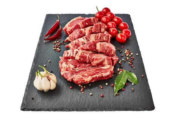 Biber ve domates siyah arduvaz tahta üzerinde taze çiğ dana biftek. Beyaz arka plan üzerinde izole. Kopya alanı