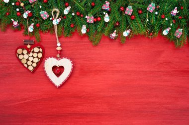 Kırmızı ahşap arka plan, kopya alanı üzerinde dekoratif kalpleri ile Noel köknar ağacı.