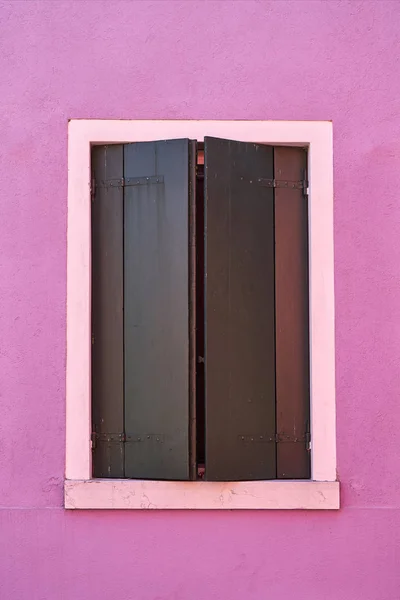 Window with green shutter on pink wall. Italy, Venicw, Burano island.