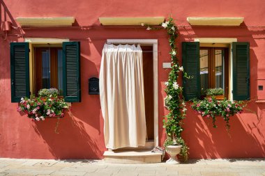 Burano Adası üzerinde çiçekli kırmızı evin önüne. Venedik, İtalya